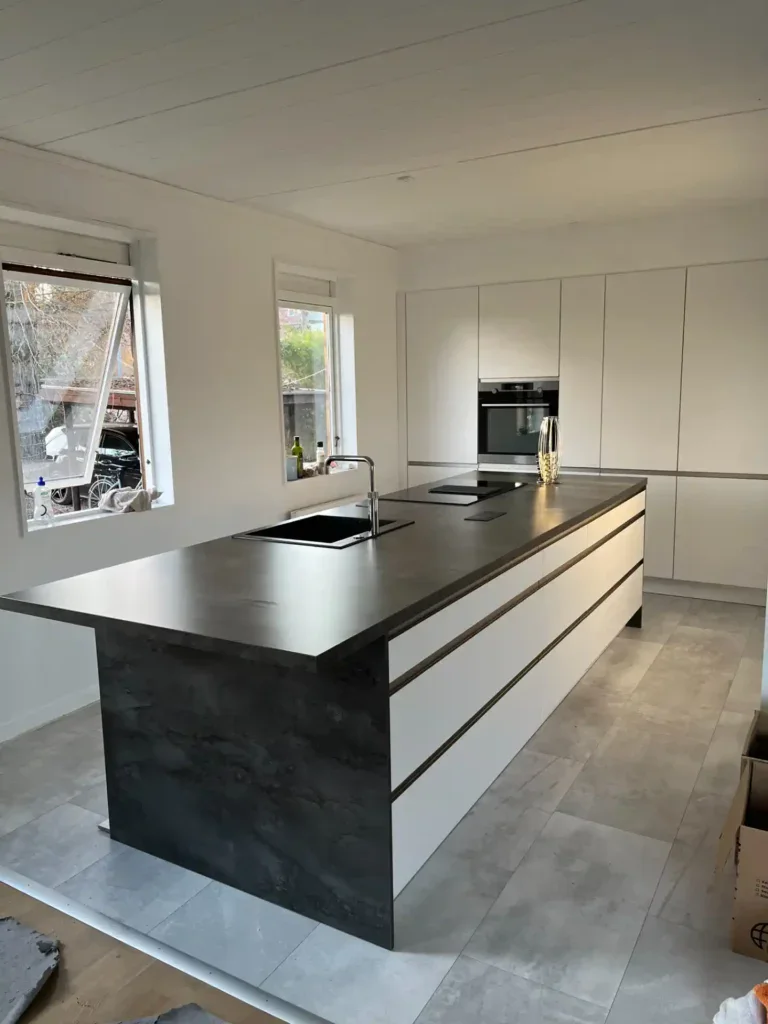 Moderne køkken med sort og hvidt design og stor ø i midten.