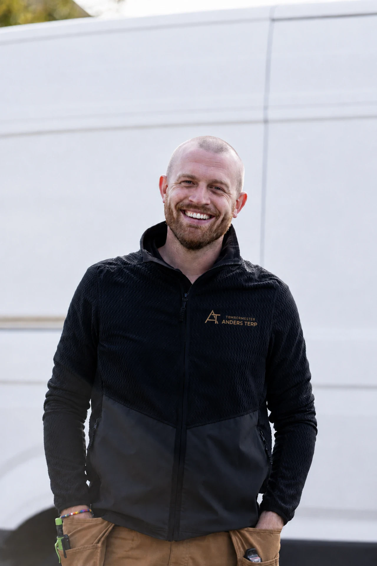Tømrermester Anders Terp smilende foran en hvid lastbil.