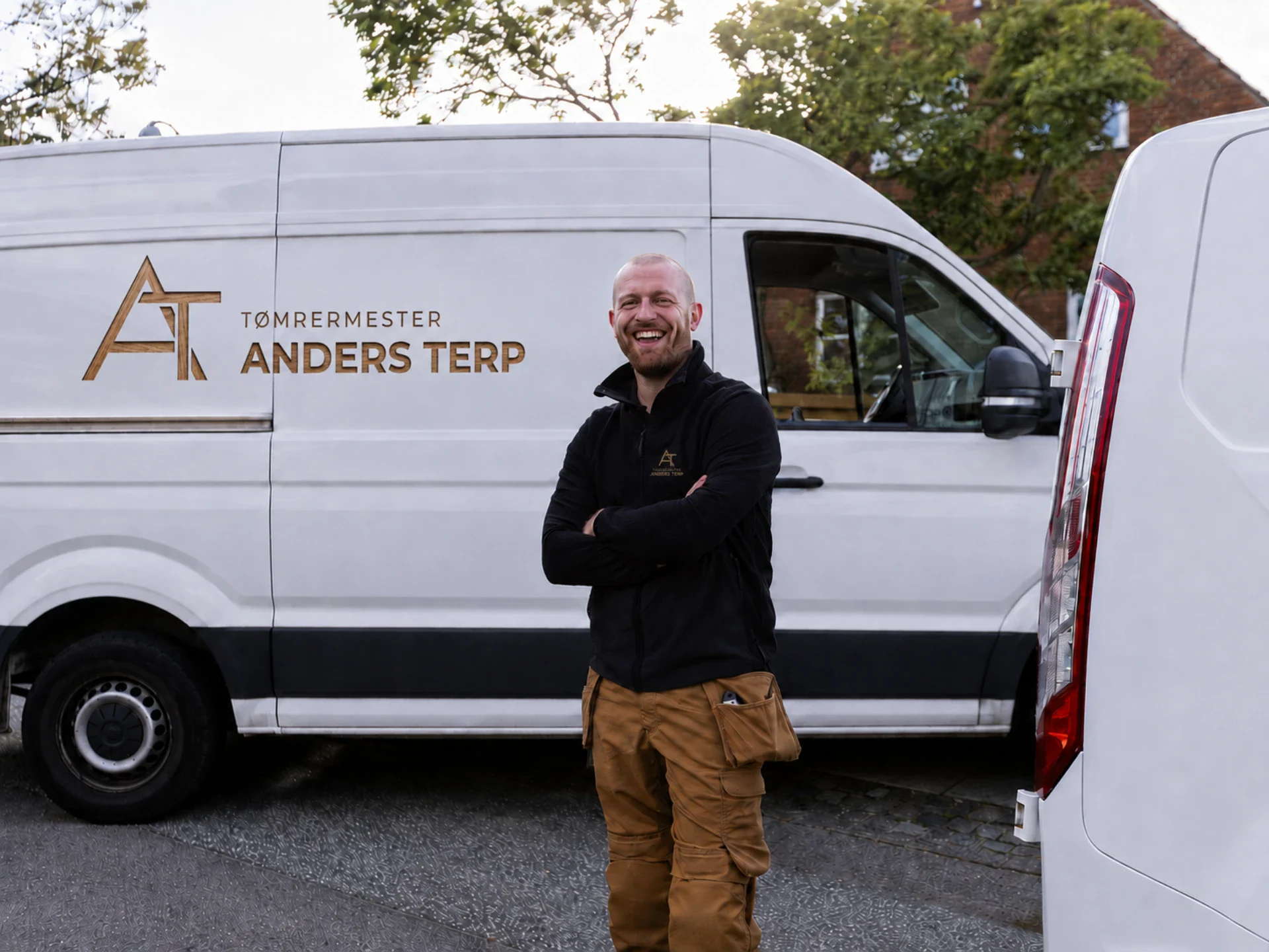 Tømrermester Anders Terp foran firmabil med logo.