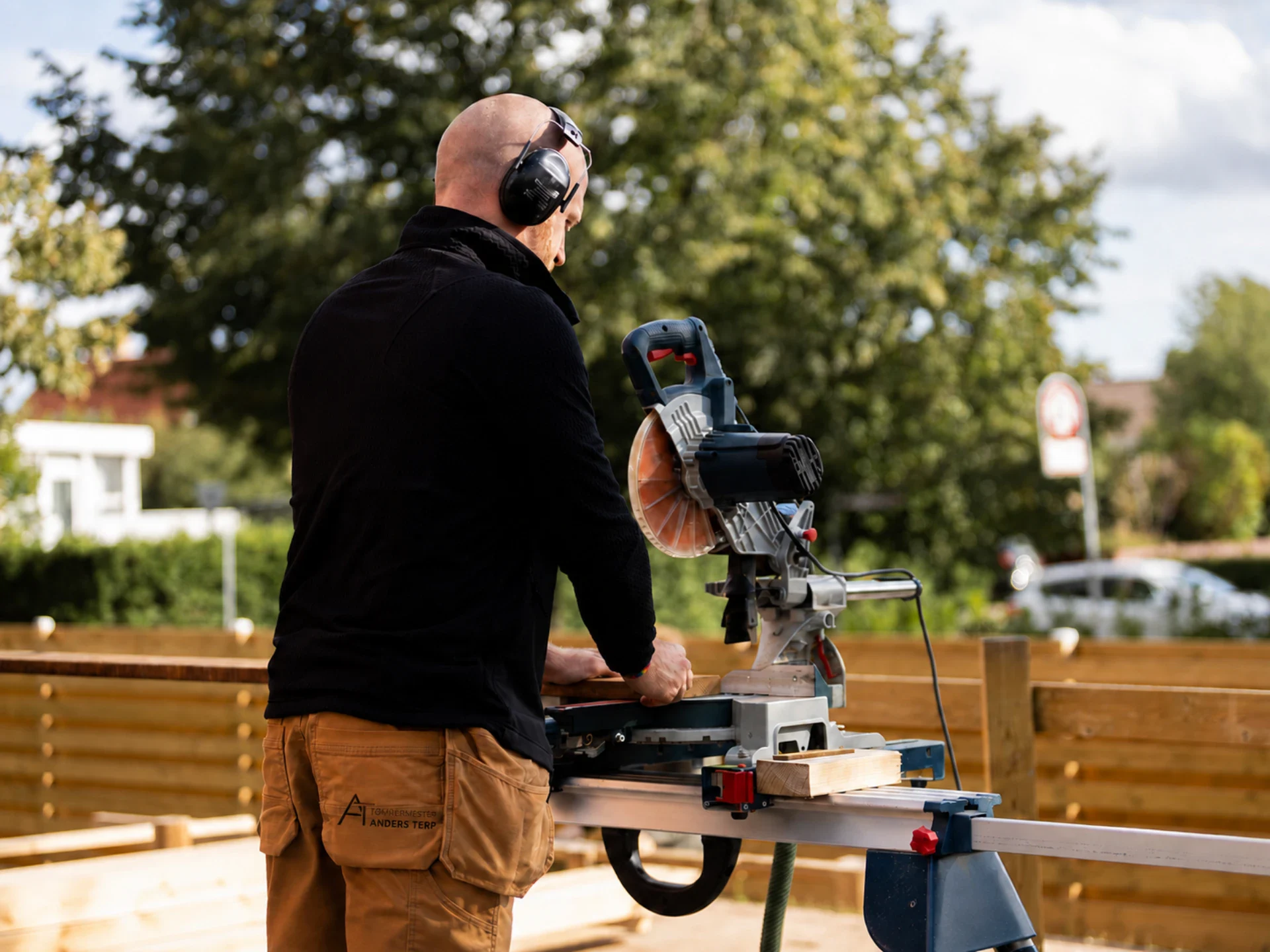 Tømrer arbejder med sav i udendørs terrassebyggeri.
