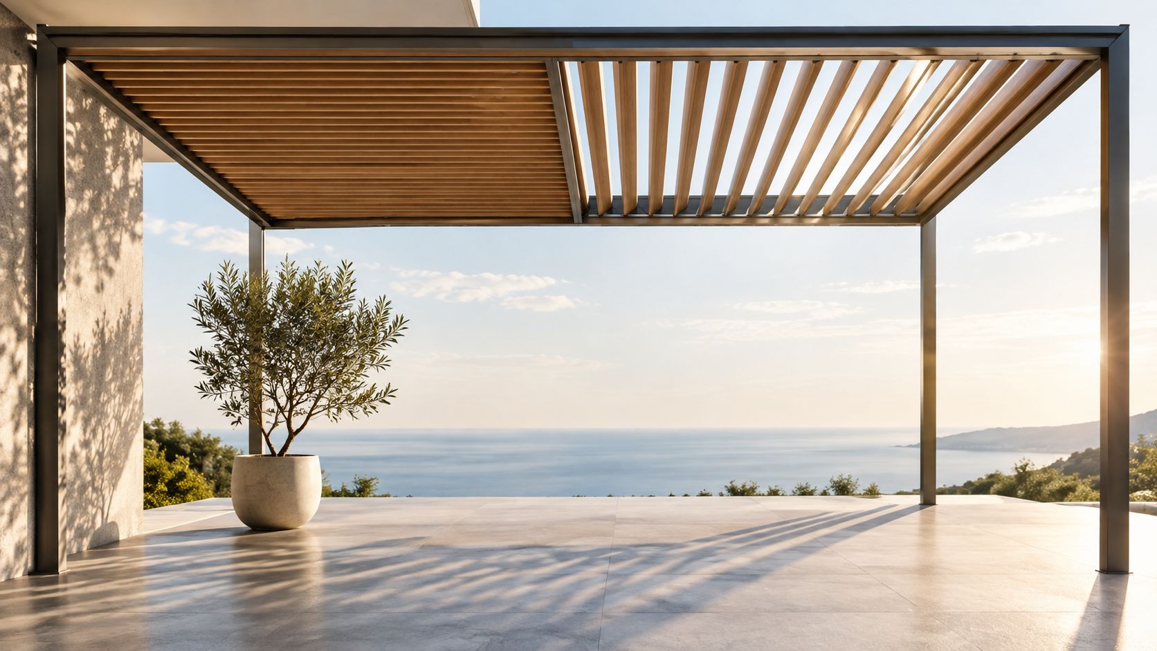 En elegant overdækket terrasse med pergola, moderne fliser og en olivenplante med udsigt over det glitrende hav.